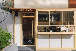 極簡店面外觀，搭配木質遮簷與玻璃窗，展示咖啡製作設備。