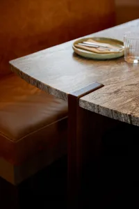 A granite countertop with a wooden support, featuring a plate of cutlery and a glass.