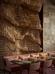 Modern restaurant interior with a textured, wavy wood wall and comfortable seating arrangement.