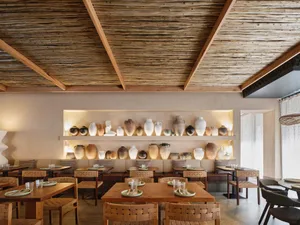 Modern restaurant interior featuring wooden furniture and a wall display of ceramic vases.