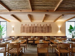 A restaurant interior featuring wooden tables, chairs, and ceiling, with decorative elements and plants.