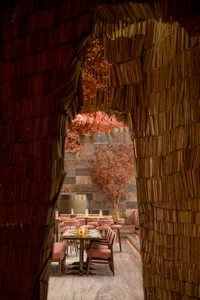 A cozy restaurant interior with tables set for service, surrounded by natural materials like thatch and wood.