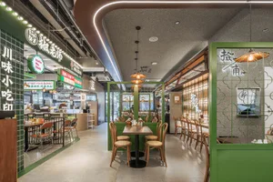 A modern restaurant interior with green-themed decor, wooden furniture, and industrial lighting fixtures.