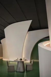 A minimalist modern restaurant interior with white concrete walls and a sleek dining table.