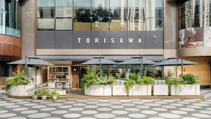 Modern urban retail storefront with concrete and glass storefront, greenery planters, and large glass windows.