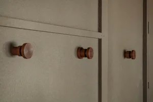 Minimalist design of wooden handles on a smooth, neutral-colored wall.