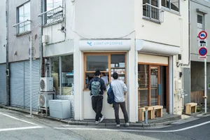 A modern corner coffee shop with white walls and a glass front window.