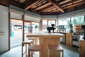 A wooden interior space with an industrial aesthetic, featuring stools, a coffee machine, and counter.