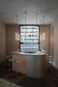 A modern bar with a glass display of bottles and a concrete counter.