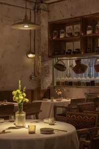 A rustic, modern restaurant interior features wooden furnishings and concrete accents.