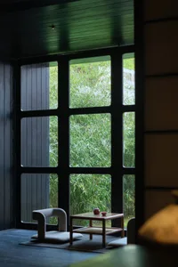 Modern living room featuring wooden furniture and a large window with a green outdoor view.