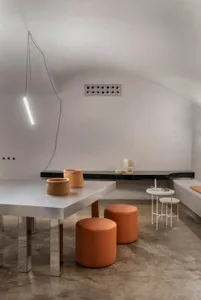 Modern cafe interior featuring concrete tables, leather stools, and metal accents.