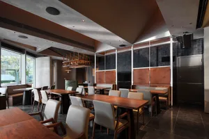 A modern restaurant interior featuring wooden tables and concrete walls.