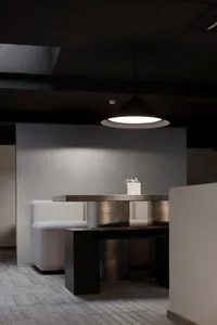 Interior design featuring modern black metal booth seating with white cushions and a black table under a black pendant light.