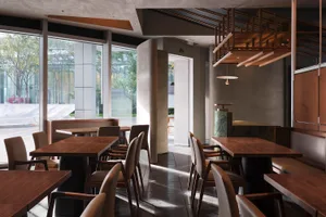 Modern restaurant interior with wooden tables, concrete flooring, and metallic accents.