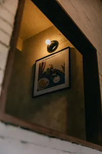 Concrete interior of a coffee shop with framed art depicting a coffee-making scene.