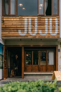 Modern industrial storefront with wooden façade, large windows, and overhead lights inside.