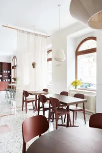 A minimalist cafe interior with wooden tables and chairs.