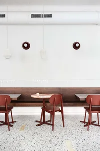 A modern coffee shop with a round pink marble table and terrazzo flooring.