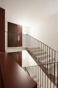 A modern interior space featuring a concrete staircase with dark railings and tiled walls.