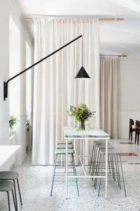 A modern kitchen with a marble table and stools.