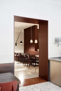 A modern minimalist restaurant interior featuring wood tables and terrazzo flooring.
