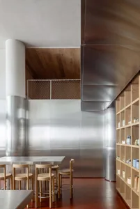 An industrial-looking commercial space featuring metallic walls and wooden furniture.