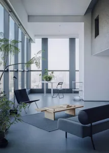 Modern minimalist living room with blue accents, featuring wooden coffee table, black leather chair, and large windows overlo