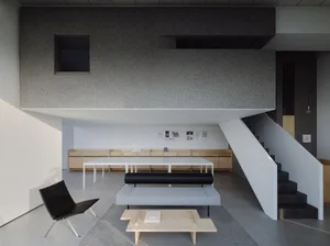 A modern minimalist living room with a concrete ceiling and minimalist furniture.
