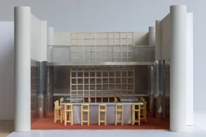 A modern restaurant bar with metal tables and wooden barstools.