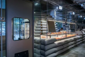 A bakery interior with a modern industrial design featuring glass, concrete, and canvas materials.