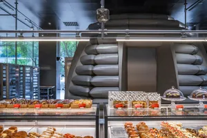 A modern bakery interior with glass walls and shelves filled with baked goods.