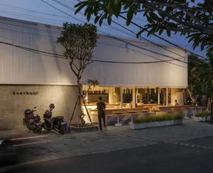 Modern, minimalist exterior of a coffee shop featuring vertical metal panels and a concrete storefront.