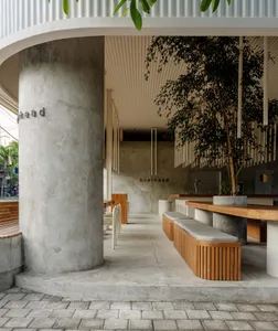 A minimalist food hall with concrete walls, wooden benches, and pendant lighting.