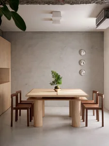 A modern wooden dining table with chairs in a minimalist interior design setting.