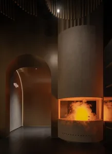 Modern living room with industrial concrete interior design, featuring a large fireplace with a warm, flickering flame and sm