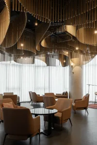 A modern lobby featuring wooden accent pieces and large windows with white curtains.
