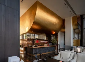 Industrial-themed restaurant bar interior with metallic wall and seating area.