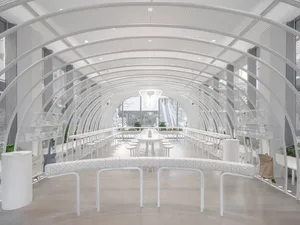 A minimalist restaurant with white arches, metal tables, and glass walls.