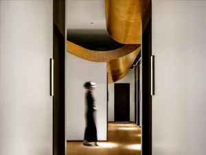 A modern interior corridor with a metallic accent wall and a person walking.
