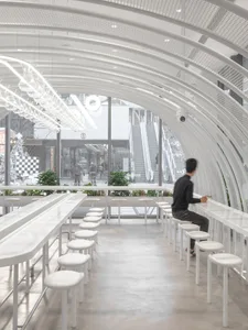 A modern minimalist cafe interior with white materials and concrete flooring.