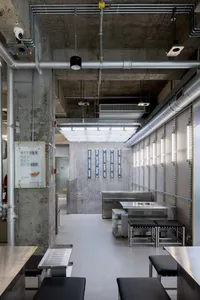 Industrial-style restaurant kitchen with concrete walls, metal countertops, and stainless steel equipment.