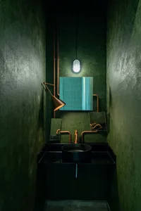 Modern bathroom with metallic elements, including sink, faucet, and mirror, featuring a minimalist design.