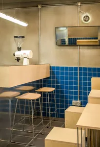 Industrial-style cafe interior with blue metallic tiled countertop and white bar stools