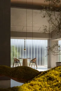 A modern restaurant interior featuring a minimalist design with concrete and glass elements.
