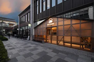 Modern storefront with concrete walls, glass panels, and wooden benches.