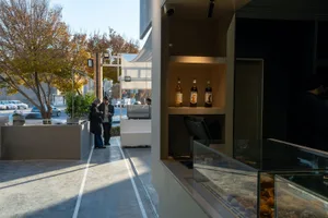 Modern street-side cafe with white concrete exterior and interior, showcasing minimalist design elements.