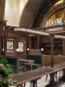Indoor restaurant interior with wooden tables and chairs, green booth seating, and modern lighting fixtures.