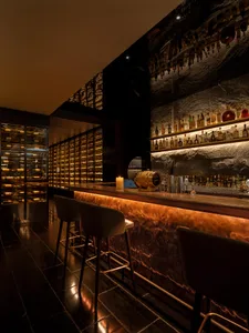 Modern industrial bar area with metallic counter, glass shelves, and candle light.