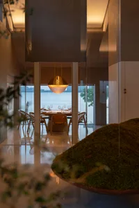 A modern elegant restaurant featuring metallic bronze lighting and minimalist concrete flooring.